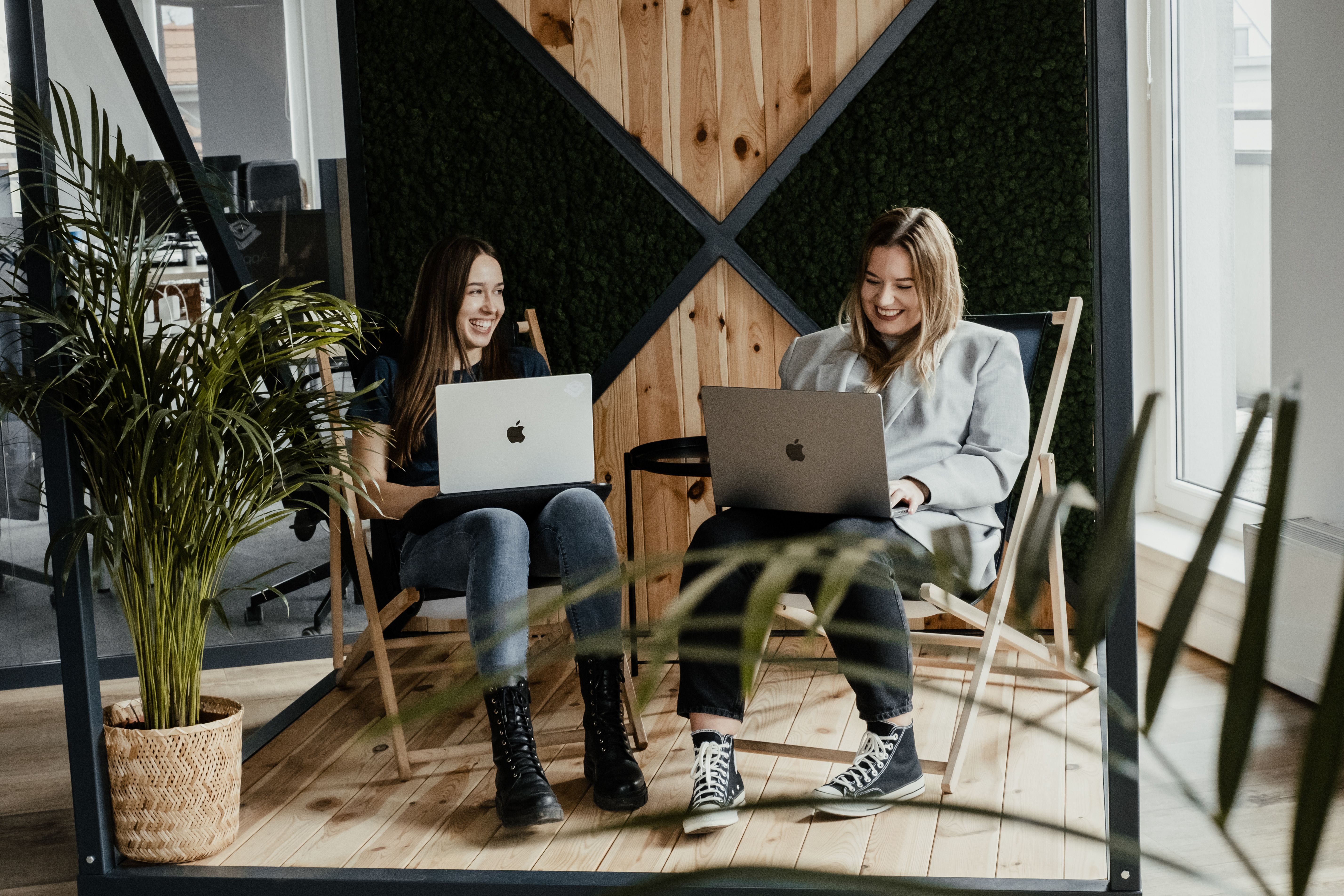 Two women with MacBooks on beach chairs